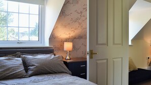 Ein Schlafzimmer mit Bett, Nachttisch, Lampe und einer Tür zu einem anderen Raum.