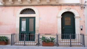 A building with two doors, each with a number plaque, and a metal fence in front. - Talè Talè Apartment just 90m from the sandy beach (Marina di Ragusa)