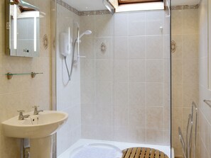 A modern bathroom with a glass-enclosed shower, a sink with two faucets, and a bathtub.