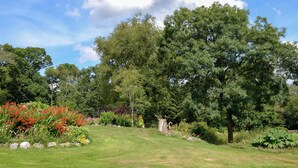 A well-maintained garden with a variety of plants and trees, a grassy lawn, and a stone pathway. - Low Cordorcan - UK5891 (Wood of Cree, near Newton Stewart)