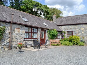 A stone cottage with a gravel driveway, a wooden bench, and a small garden with flowers and shrubs. - Low Cordorcan - UK5891 (Wood of Cree, near Newton Stewart)