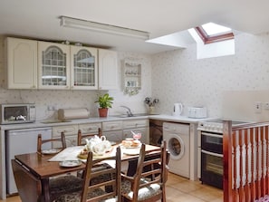 A compact kitchen with a dining area, a washing machine, and a skylight.