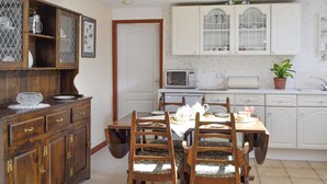 A traditional kitchen with wooden cabinets, a dining table with chairs, and a microwave. - Low Cordorcan - UK5891 (Wood of Cree, near Newton Stewart)