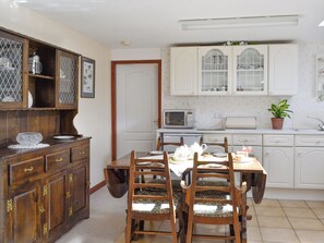 A traditional kitchen with wooden cabinets, a dining table with chairs, and a microwave.