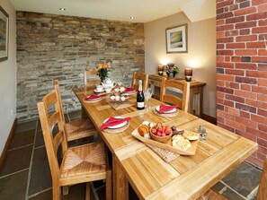 A wooden dining table set with plates, cutlery, and a bottle of champagne.