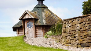 Une petite maison en bois avec un toit de chaume, une porte en bois et un mur en pierre.