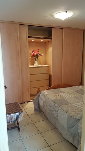 Une chambre à coucher avec un lit, une petite table, une commode et un placard.