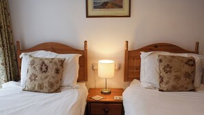 A hotel room with two beds, a nightstand, a lamp, and a painting on the wall. - 4 bedroom accommodation in Ambleside (Ambleside)