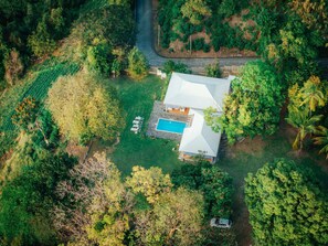 An aerial view of a house with a swimming pool, surrounded by dense greenery and a road. - Villa du Morne d'Orange (Saint-Pierre)