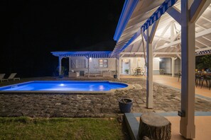An outdoor pool area with a covered seating area and a patio.
