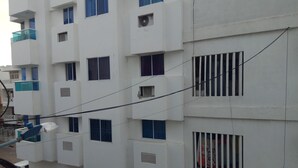 A multi-story building with a white facade, blue window frames, and air conditioning units. - Cozy and quiet room in family house (Cartagena)