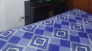 A room with a bed with a patterned blue and white bedspread, a black dresser with a television on top, and a wooden wardrobe. - Cozy and quiet room in family house (Cartagena)