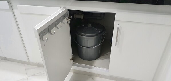 A kitchen cabinet with a built-in trash bin.