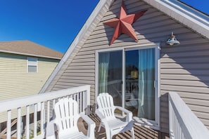 A building with a large star decoration, a sliding glass door, and two white chairs on a deck.