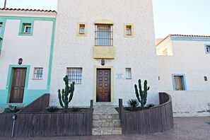 Stunning entrance with a central door, flanked by two cacti and a small set of stone steps.