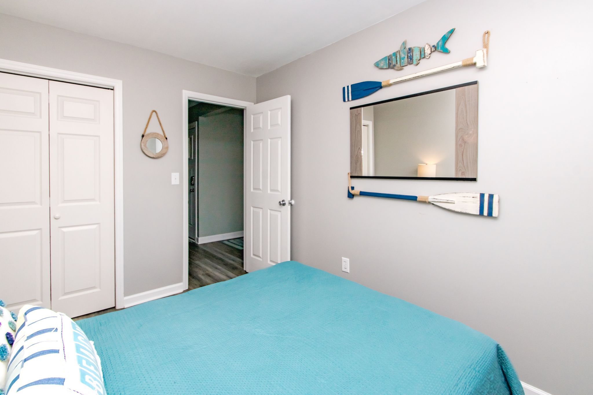 A bedroom with a bed, a door, a mirror, and a wall decoration.