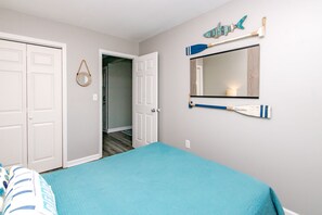 Un dormitorio con cama, una puerta, un espejo y un adorno en la pared.