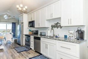 A modern kitchen with white cabinets, a microwave, a toaster, and a coffee maker. - Legacy Beach House - Gorgeous 4BR Oceanfront Duplex! (North Topsail Beach)