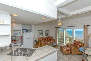 A compact living space with a kitchen, dining area, and a balcony with a view of the sea.
