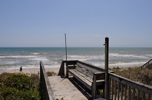 A wooden boardwalk leading to a beach with waves crashing onto the shore.