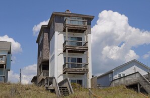 A multi-story building with balconies, a staircase, and a clear sky.