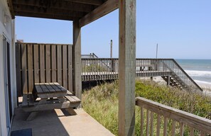 A wooden deck with a bench and a staircase leading to a beach.