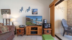 Un soggiorno con televisione, diffusori audio e mobile TV in legno.