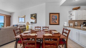 A dining area with a table set for six, surrounded by wooden chairs with red cushions. - Sonoran Sea E-401 Feeling tip' Sea In Paradise Bright Oceanfront Condo (Puerto Peñasco)