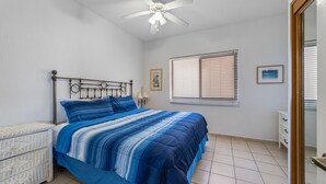 A bedroom with a bed, a nightstand, a dresser, a ceiling fan, a window with blinds, and a door. - Sonoran Sea E-401 Feeling tip' Sea In Paradise Bright Oceanfront Condo (Puerto Peñasco)