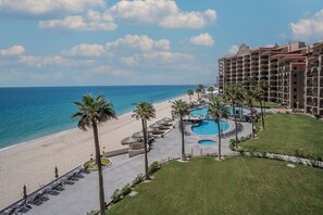 Un resort con spiaggia, area piscina e un edificio a più piani.