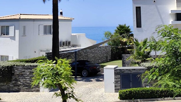 Zona residencial costera con edificios blancos, una palmera y cielo azul despejado.