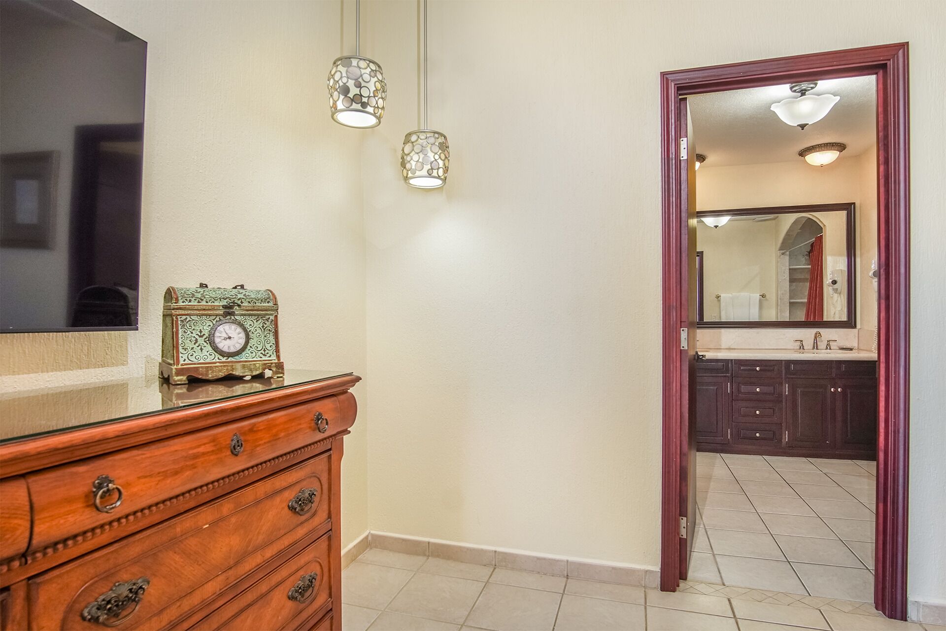 Une salle de bain avec un meuble-lavabo, un miroir et une horloge posée sur le comptoir.