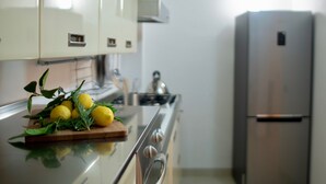 A kitchen with a stainless steel refrigerator, a wooden cutting board with lemons and herbs, and a stove. - Elegant apartment, in the heart of the historic center of Noto, for 2 to 6 guests (Noto)
