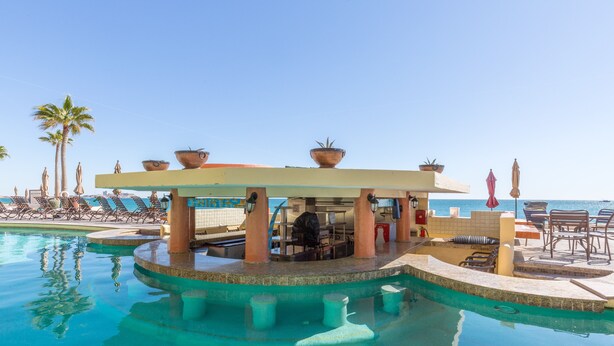 Area piscina con sedie a sdraio, un bar e vista sull'oceano.