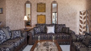 Un soggiorno con divani a fantasia, un tavolino da caffè e specchi decorativi alle pareti.