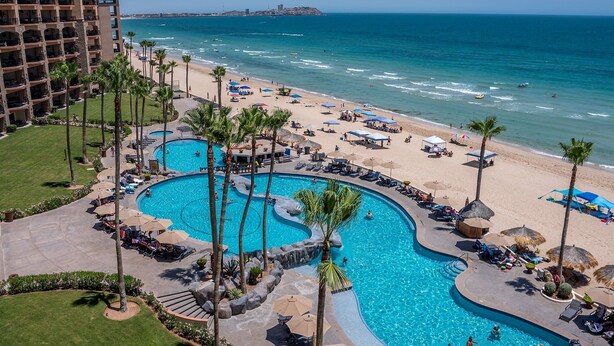 Un resort con una piscina grande, playa y vista al océano.