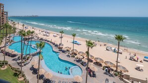 Un resort con amplia zona de piscina, playa y vista al océano.