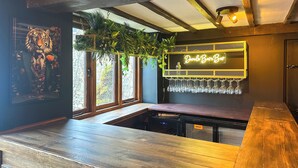 Una zona de bar con mostrador de madera, un letrero de neón que dice 'DuraLle BarnBar' y un cartel que indica 'HOST'.