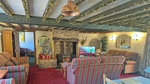 Una sala de estar acogedora con sofás a rayas, una chimenea, un televisor y decoración festiva.