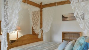 A bedroom with a wooden headboard, a bed with a plaid blanket, and a nightstand with a lamp. - 2 bedroom accommodation in Lostwithiel (Lostwithiel)