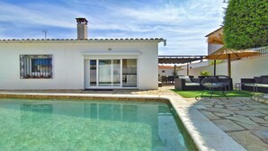 Une maison moderne dotée d’une piscine, d’un patio avec mobilier d’extérieur et d’un jardin bien entretenu.