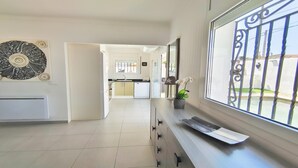 Une cuisine moderne avec des meubles blancs, un lave-vaisselle et une fenêtre ornée de barreaux en fer décoratifs.