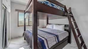 Ein Stockbett mit einer Leiter, ein Fenster mit Blick und eine gestreifte Bettdecke.