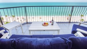 A balcony with a view of the beach, a table with a bottle and glasses, and blue cushioned seating. - Sonoran Sea East 711 Beautiful Spacious Ocean View Condo (Puerto Peñasco)