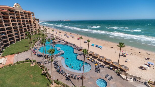 A resort with a large pool area, beach access, and a view of the ocean.