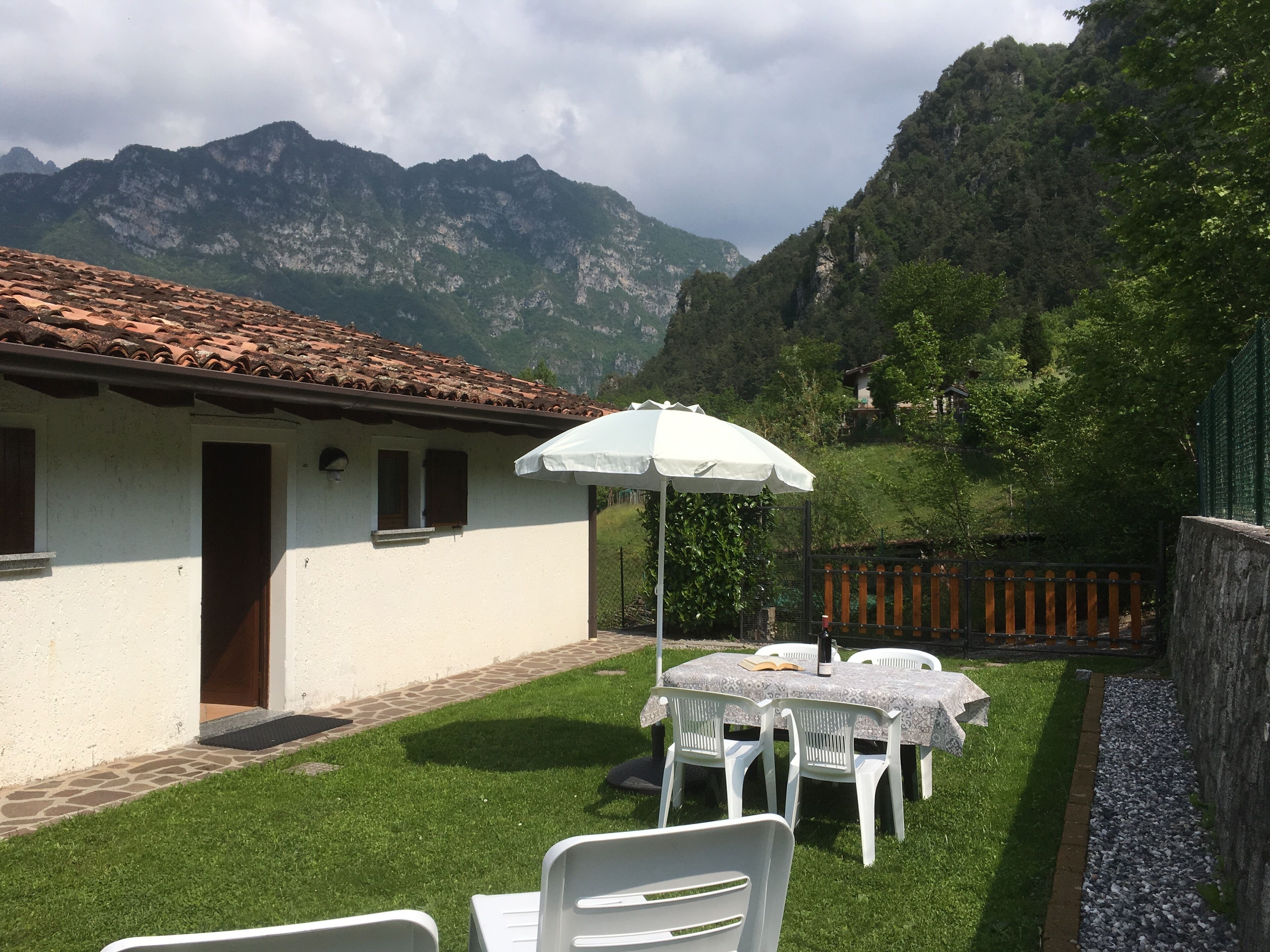 A patio with a table and chairs, a white umbrella, and a view of mountains.