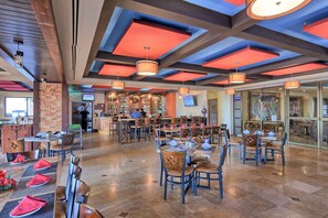 Un restaurant spacieux avec de hauts plafonds, des poutres apparentes et différents types de mobilier, notamment des tables et des chaises.