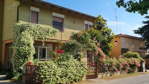 A two-story building with a balcony, a gated entrance, and a small garden with flowering plants. - Renovated and equipped apartment in Cervia-Milano Marittima (Cervia)