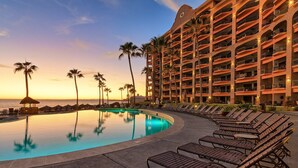 A hotel pool area with lounge chairs and palm trees at sunset. - Sonoran Sea E-805 Barefoot @ Sea Retreat Stunning Oceanfront Condo (Puerto Peñasco)