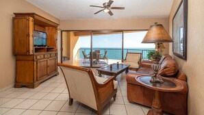 A spacious balcony with a view of the ocean, furnished with leather sofas, a coffee table, and a TV. - Sonoran Sea E-805 Barefoot @ Sea Retreat Stunning Oceanfront Condo (Puerto Peñasco)